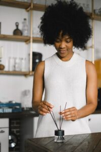 A woman enjoys a calming aromatherapy session indoors with a reed diffuser.